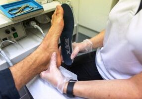 A podiatrist fitting a patient for orthotics at Foot Talk Podiatry